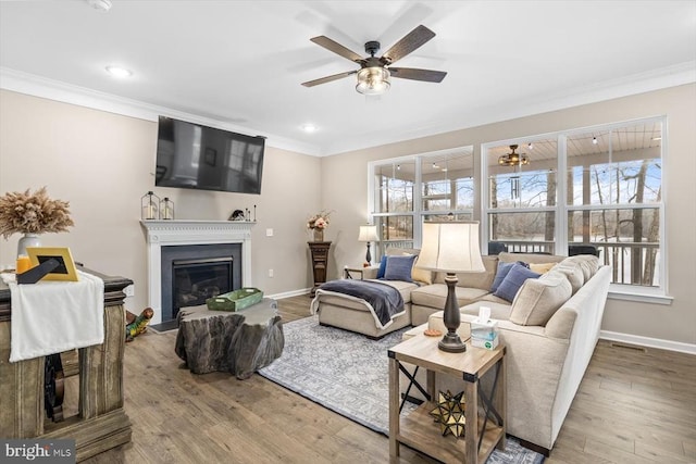 living room with crown molding, ceiling fan, hardwood / wood-style flooring, and a healthy amount of sunlight