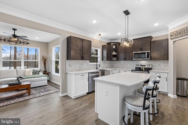 kitchen featuring a kitchen island, white cabinetry, a breakfast bar area, dark brown cabinetry, and stainless steel appliances