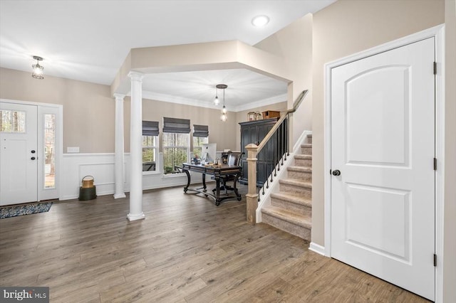 foyer entrance featuring decorative columns, ornamental molding, and hardwood / wood-style flooring