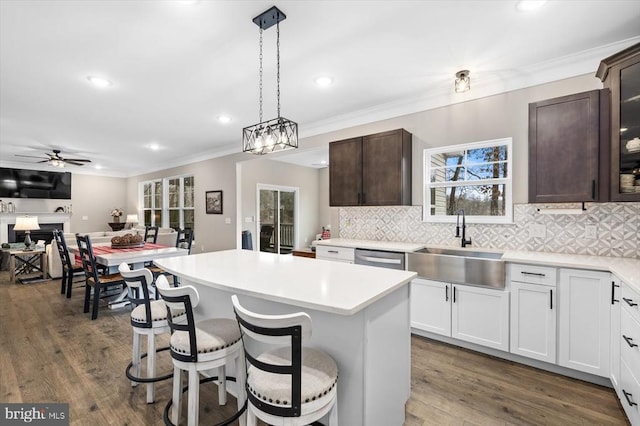 kitchen with a kitchen island, sink, a breakfast bar area, hanging light fixtures, and dark brown cabinetry