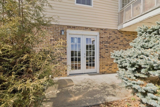 property entrance featuring french doors, brick siding, and a patio area