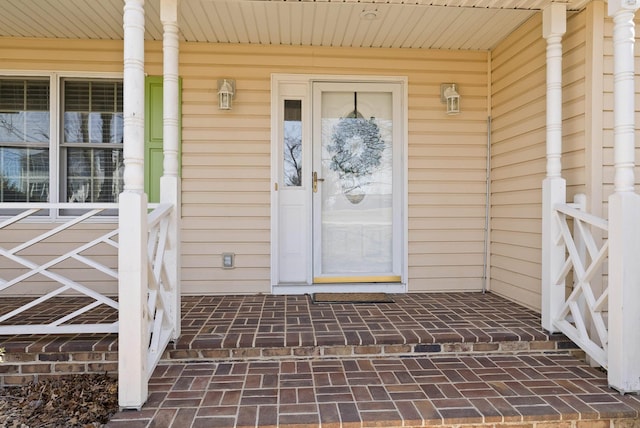 view of exterior entry featuring brick siding and a porch