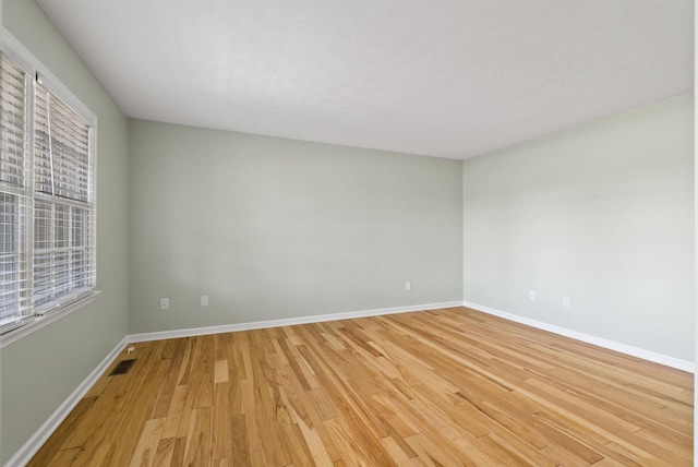 unfurnished room featuring baseboards, visible vents, and light wood-type flooring