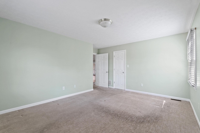 unfurnished room with baseboards, visible vents, and carpet floors