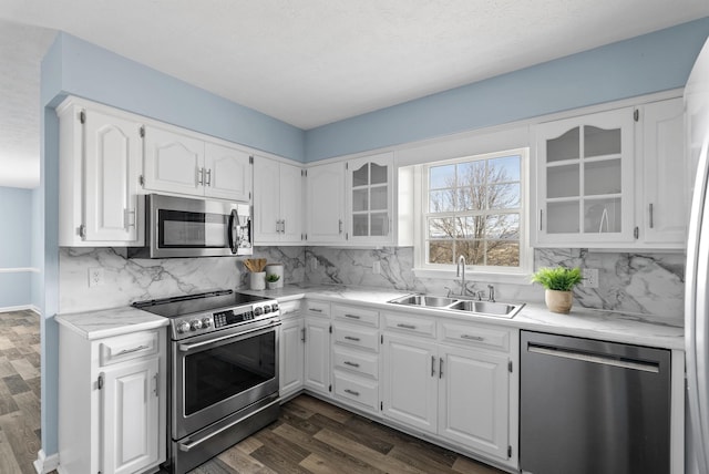 kitchen featuring dark wood-type flooring, glass insert cabinets, appliances with stainless steel finishes, and a sink