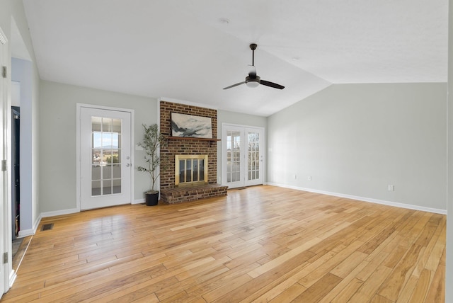 unfurnished living room featuring a wealth of natural light, light wood-type flooring, and a brick fireplace