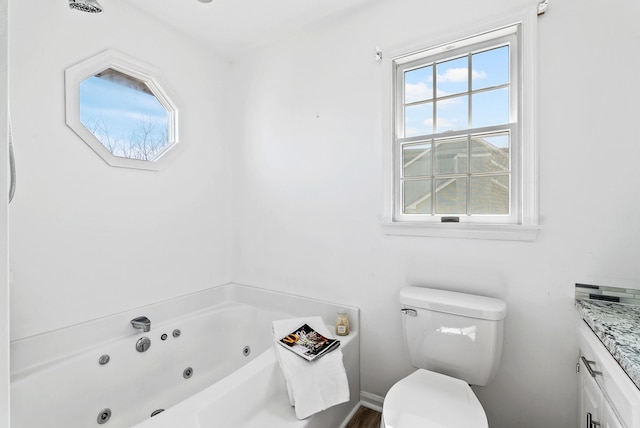 full bath with toilet, vanity, baseboards, and a whirlpool tub