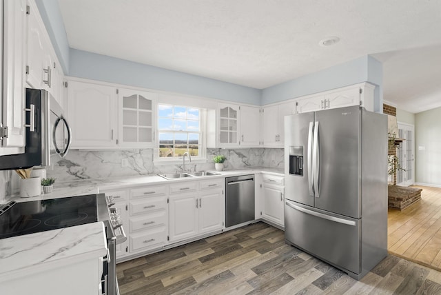 kitchen featuring dark wood-style flooring, a sink, stainless steel appliances, white cabinetry, and tasteful backsplash