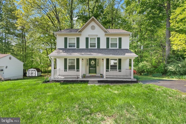 view of front of property with a porch, a storage unit, an outbuilding, a front lawn, and a shingled roof