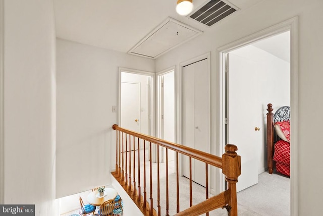 hall featuring an upstairs landing, carpet, attic access, and visible vents