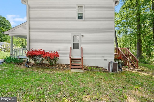 rear view of house featuring entry steps, stairs, central AC unit, and a yard