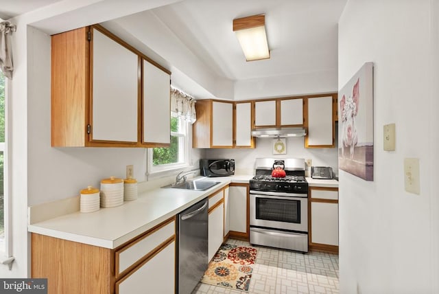 kitchen featuring under cabinet range hood, stainless steel appliances, a sink, and light countertops