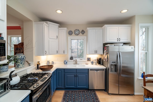 kitchen featuring sink, stainless steel appliances, white cabinets, and blue cabinets