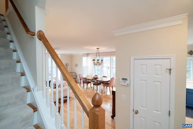 staircase featuring ornamental molding and a chandelier