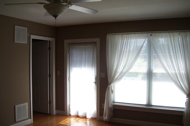 empty room featuring baseboards, visible vents, wood finished floors, and ceiling fan