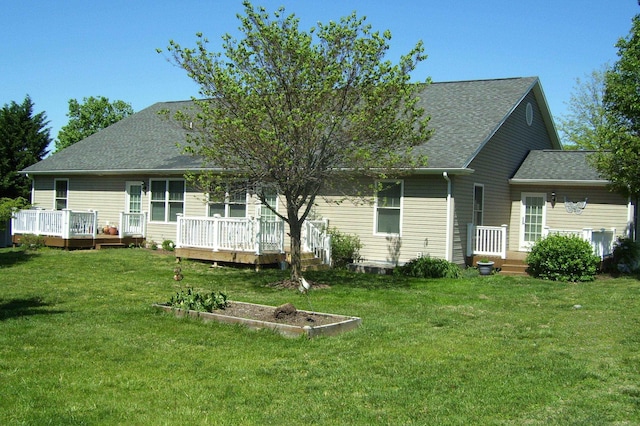 back of property with a lawn, a wooden deck, and roof with shingles