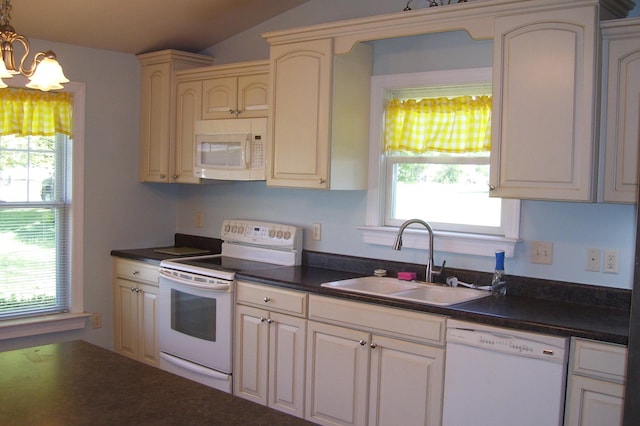 kitchen featuring dark countertops, white appliances, a chandelier, and a sink