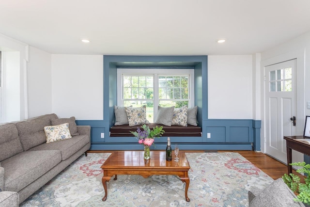 living room featuring a decorative wall, recessed lighting, wood finished floors, and wainscoting