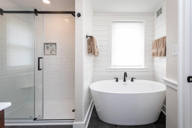 bathroom featuring visible vents, a freestanding bath, and a shower stall