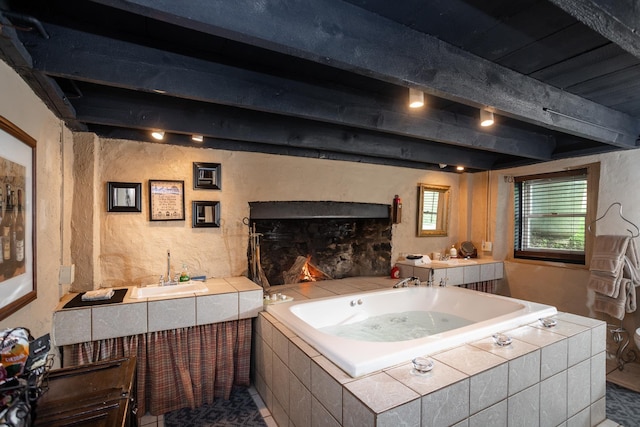 bathroom featuring vanity, beam ceiling, a garden tub, and a textured wall