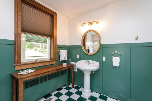 bathroom featuring tile patterned floors, a wainscoted wall, radiator, and a decorative wall