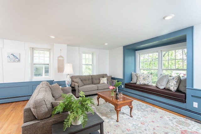 living area with recessed lighting, a baseboard radiator, and wood finished floors