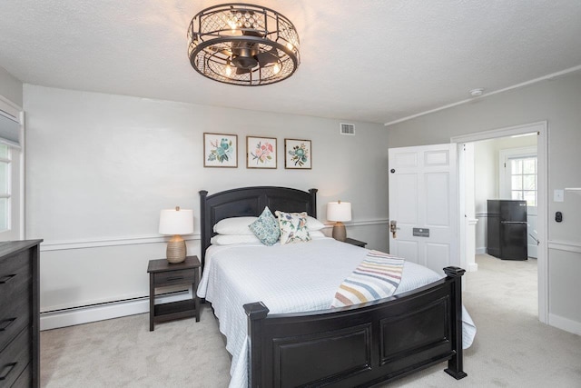 bedroom featuring light colored carpet, baseboard heating, visible vents, and freestanding refrigerator