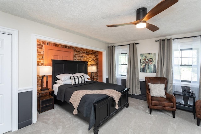 bedroom featuring light colored carpet, ceiling fan, and a textured ceiling