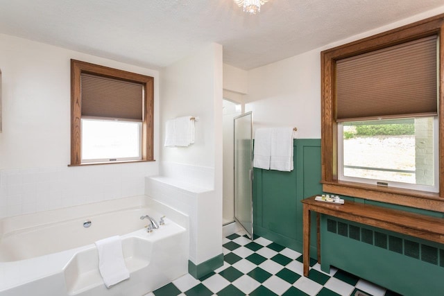 full bathroom featuring a garden tub, a wainscoted wall, radiator heating unit, a textured ceiling, and tile patterned floors