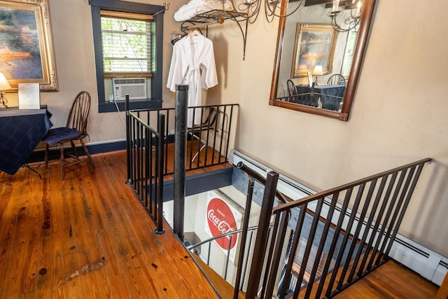 stairway with cooling unit, baseboards, and hardwood / wood-style floors