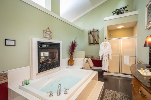 full bath featuring a garden tub, wood finished floors, a shower stall, a fireplace, and vanity