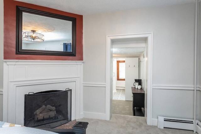 carpeted living area with a textured ceiling, a fireplace with raised hearth, a wainscoted wall, and a baseboard radiator