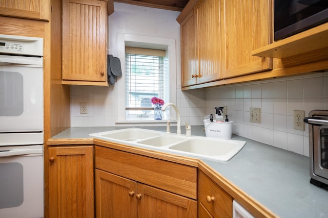 kitchen featuring double oven, brown cabinetry, backsplash, and a sink