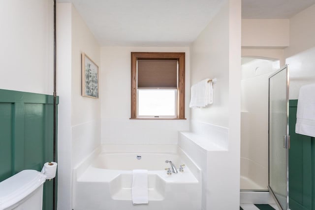 bathroom with a shower stall, toilet, and a garden tub