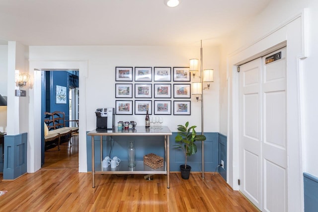 interior space with a decorative wall, wainscoting, and wood finished floors