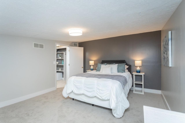 carpeted bedroom with visible vents, a textured ceiling, and baseboards