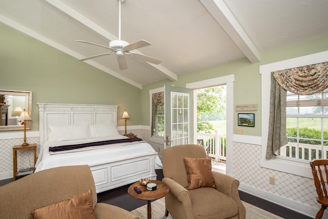 bedroom featuring a ceiling fan, lofted ceiling with beams, wood finished floors, and wainscoting