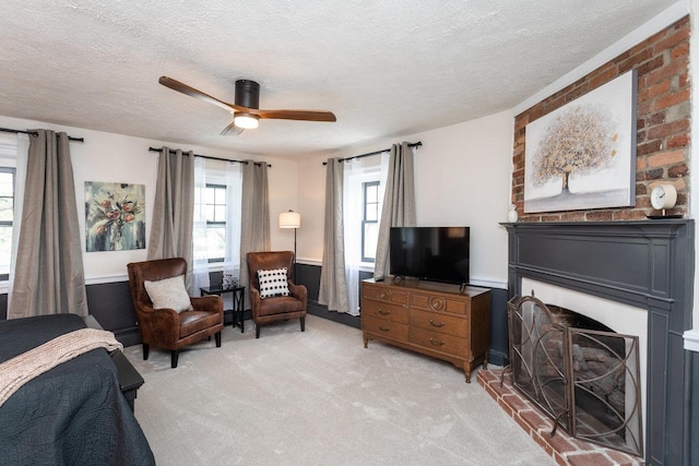 bedroom featuring a baseboard heating unit, ceiling fan, light colored carpet, a fireplace, and a textured ceiling