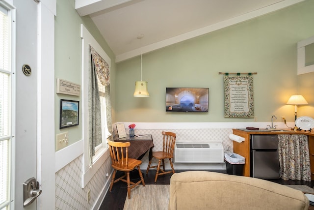 interior space featuring a wall mounted AC, vaulted ceiling, wood finished floors, and wainscoting