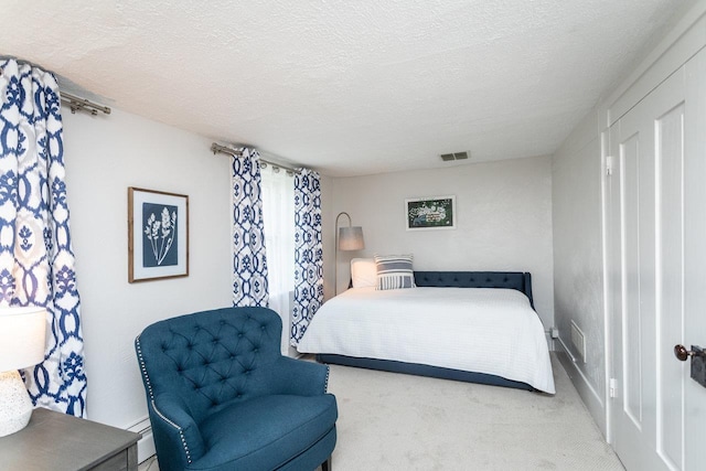 bedroom with visible vents, a textured ceiling, baseboard heating, and carpet