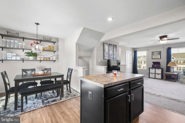 kitchen featuring ceiling fan, a center island, light wood-type flooring, and decorative light fixtures