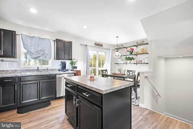 kitchen featuring sink, a center island, dishwasher, light hardwood / wood-style floors, and backsplash