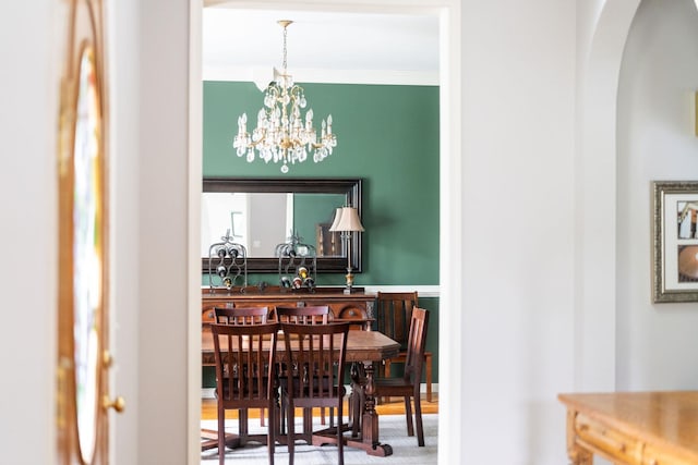 dining space with crown molding and a chandelier