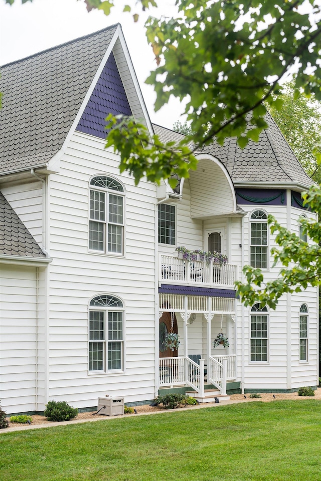 back of house with a porch, a balcony, and a lawn