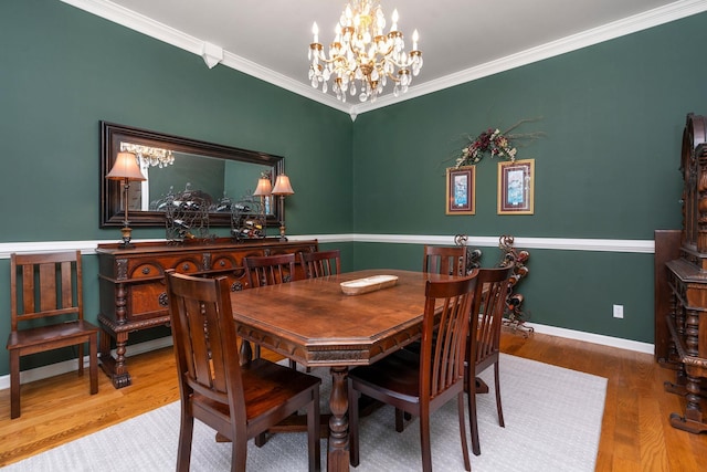 dining space featuring ornamental molding, wood-type flooring, and a notable chandelier