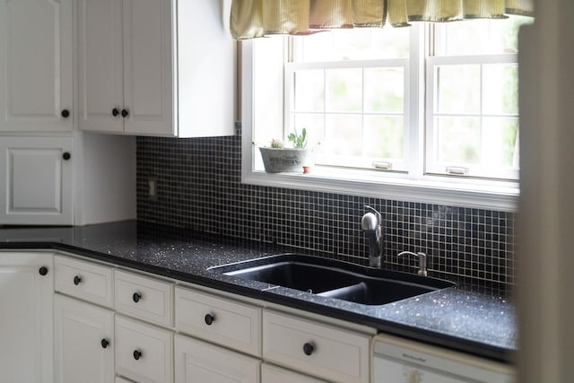 kitchen featuring backsplash, dishwasher, sink, and white cabinets