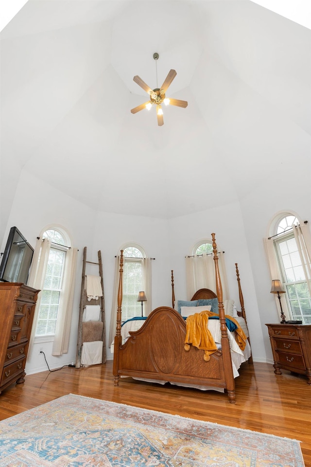 bedroom with ceiling fan, hardwood / wood-style floors, and high vaulted ceiling