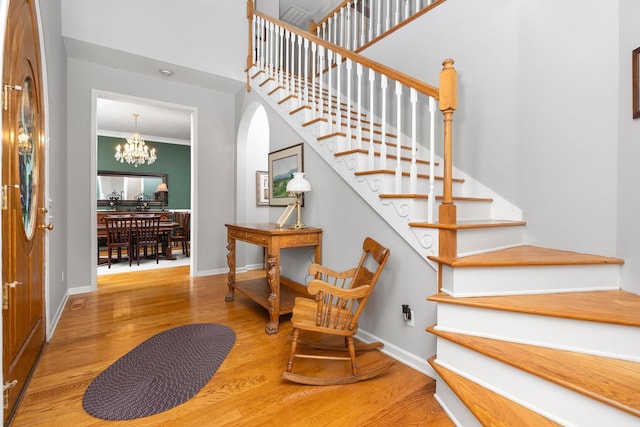 stairs with crown molding, hardwood / wood-style floors, and a notable chandelier