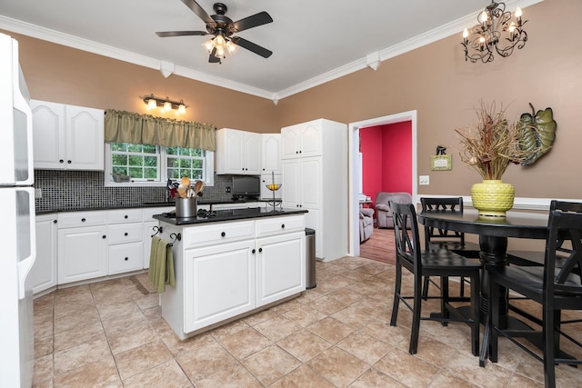 kitchen with tasteful backsplash, crown molding, white fridge, and white cabinets