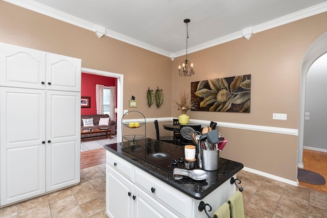 kitchen featuring white cabinetry, hanging light fixtures, dark stone countertops, ornamental molding, and a notable chandelier